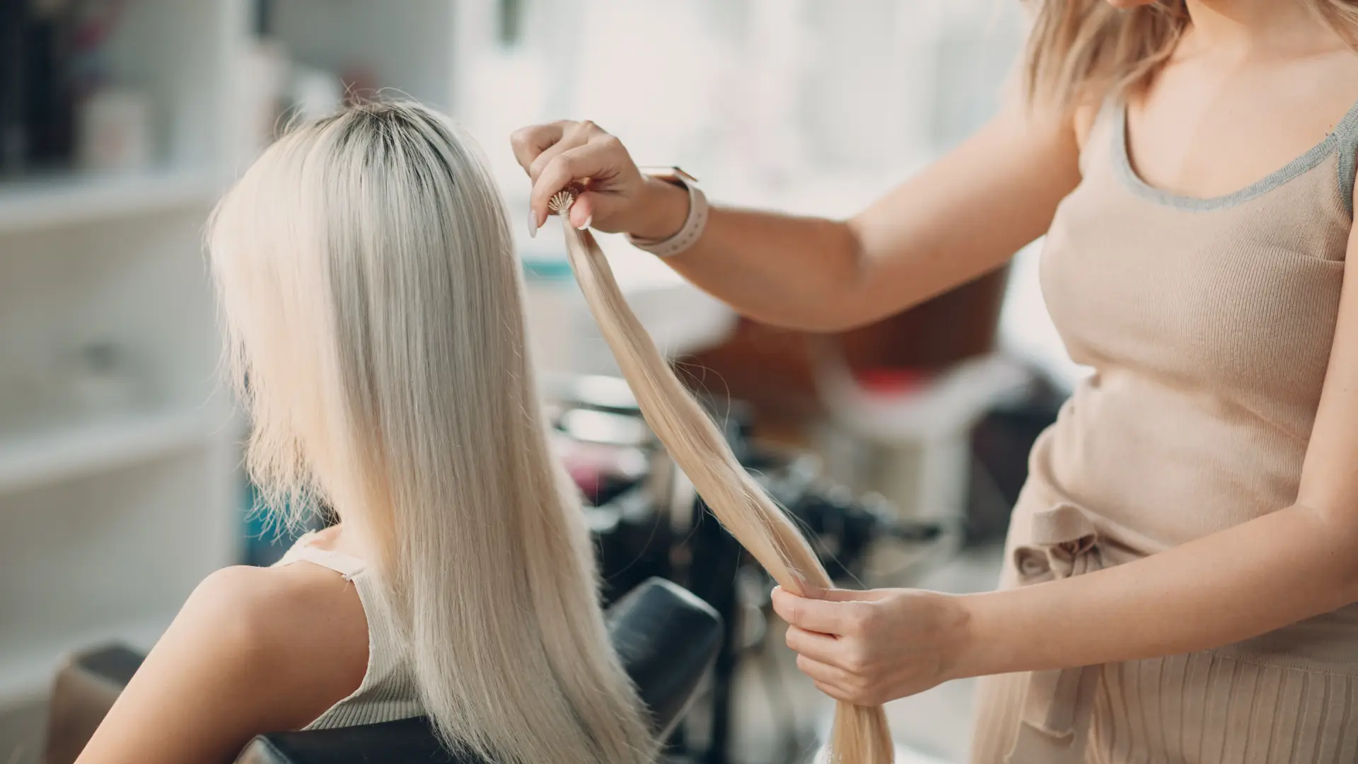 A stylist working with a client’s long, straight blonde hair